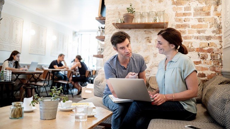Echange entre une homme et une femme devant un écran d'ordinateur dans un café