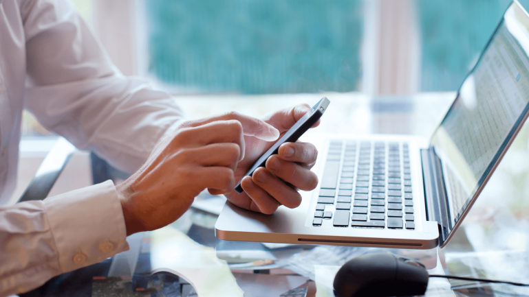 Personne utilisant un smartphone et un ordinateur portable sur un bureau