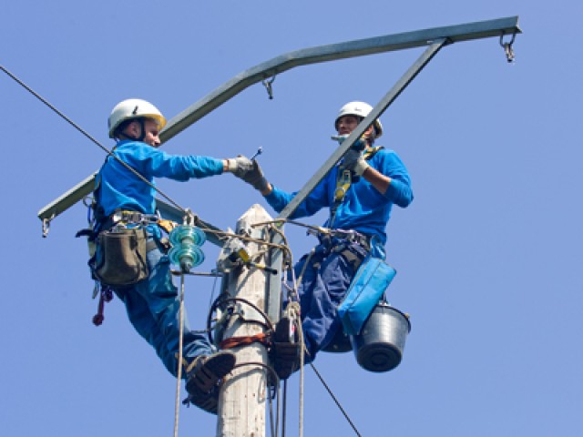 Photo de deux techniciens intervenant sur un poteau électrique
