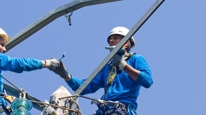 Deux techniciens en haut d'un poteau électrique
